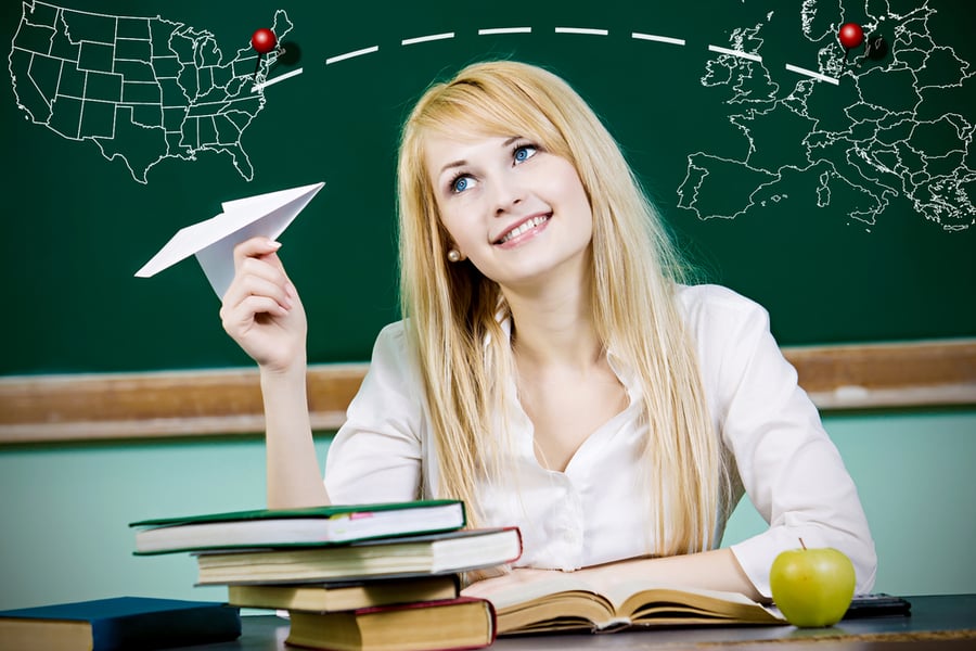 Closeup portrait happy, smiling business woman, student, teacher, girl holding paper plane, imagining, wishing flying jet isolated green chalkboard background with world travel map. Positive emotions