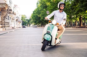 Fashion man driving a scooter in helmet in old town