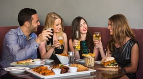 Happy friends sitting together having dinner in a restaurant