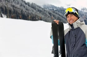 happy skier smiling with his skiis in the trail